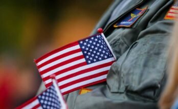 Robert Kielbowicz, who spent 4 of his 12 years in the navy at Nas Oceana, folds a flag in his jacket while applauding during the Virginia Beach, Virginia, virginia day parade on November 11, 2024.
