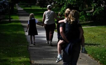 Families leave Annunciation Catholic School in Minneapolis after a mass shooting on August 27, 2025. Parents descend a sidewalk with their children.